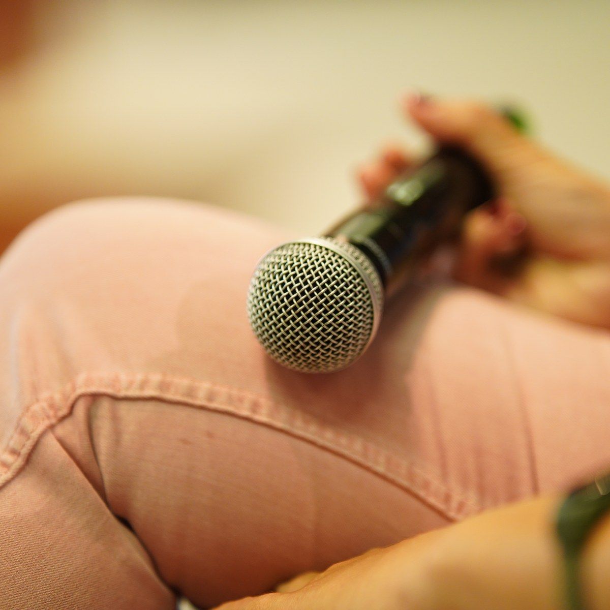 A hand holding a microphone on a lap, seen up close